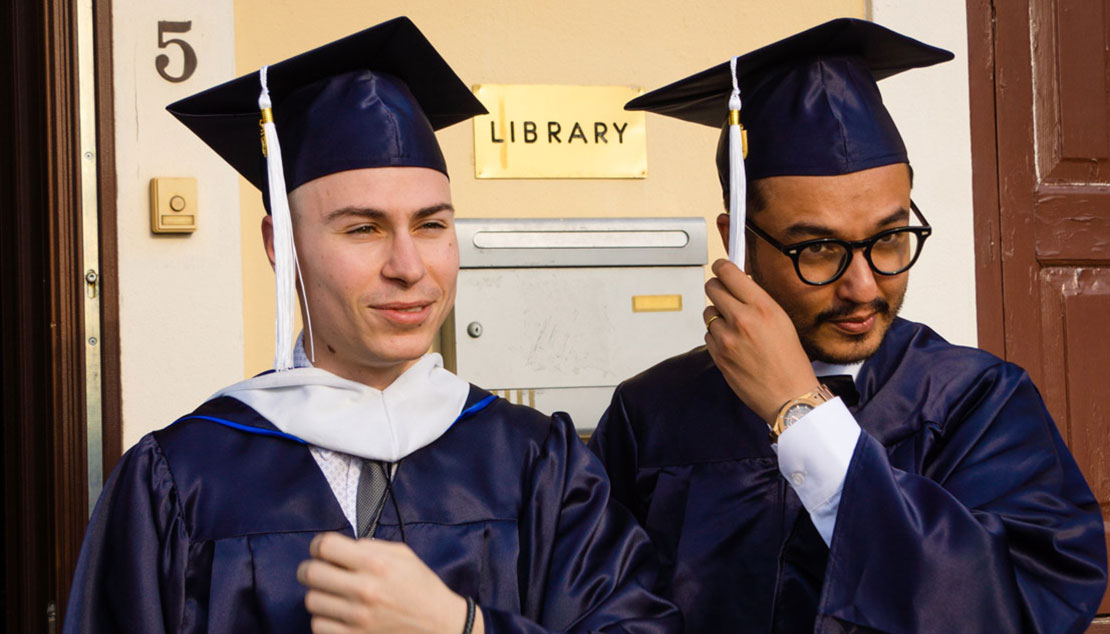 Two men graduating from Webster Athens and moving their tassel from one side to the other