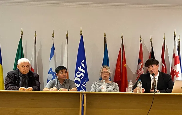 Four individuals sit at a conference panel table during the “Irregular Migration in Asia, Europe and North Africa” session at Webster Athens. From left to right: Dr. Ioannis Nomikos speaks at the microphone, followed by graduate students Dennis Acerit, Theresa Lillelund and Ignatios Nesposountni, who are presenting their research.