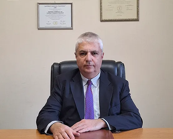 Dr. Stamoulis, business department head pose for a photo in his office desk