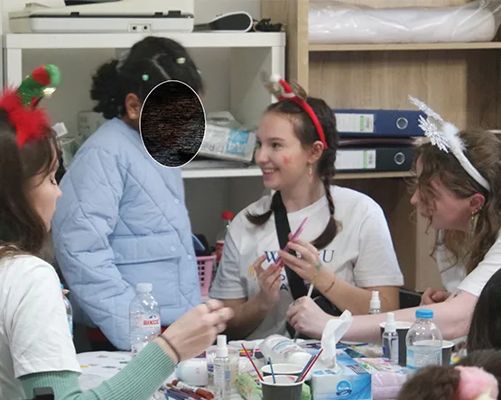 students creat face painting on a child's face